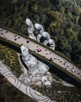 People walking on a curved bridge held by a giant stone hand in Vietnam