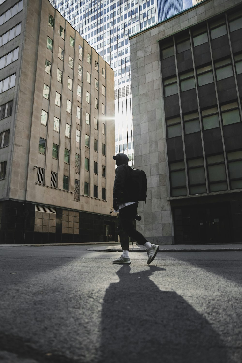 man in black jacket and black pants walking on sidewalk during daytime