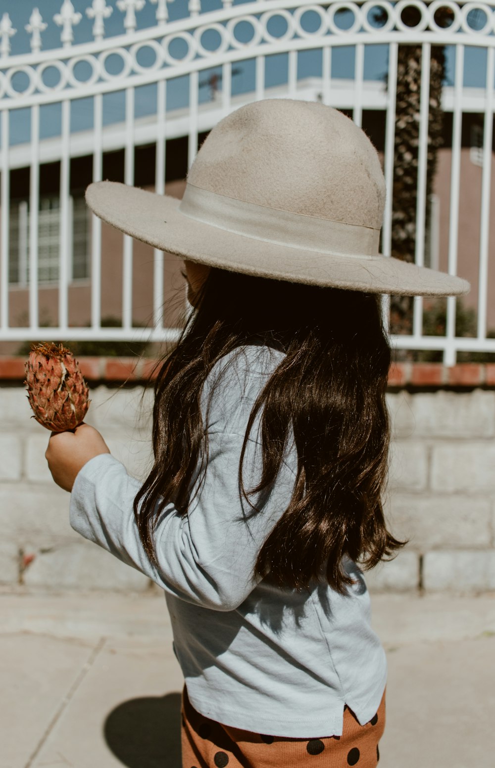 woman in white long sleeve shirt and brown straw hat holding brown fruit