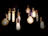 Several light bulbs with different shapes and filament designs hang against a dark background. The bulbs emit a warm glow, creating an inviting and intimate atmosphere.