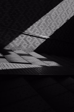 Monochrome urban street scene with dramatic lighting highlighting textures and contrasts.