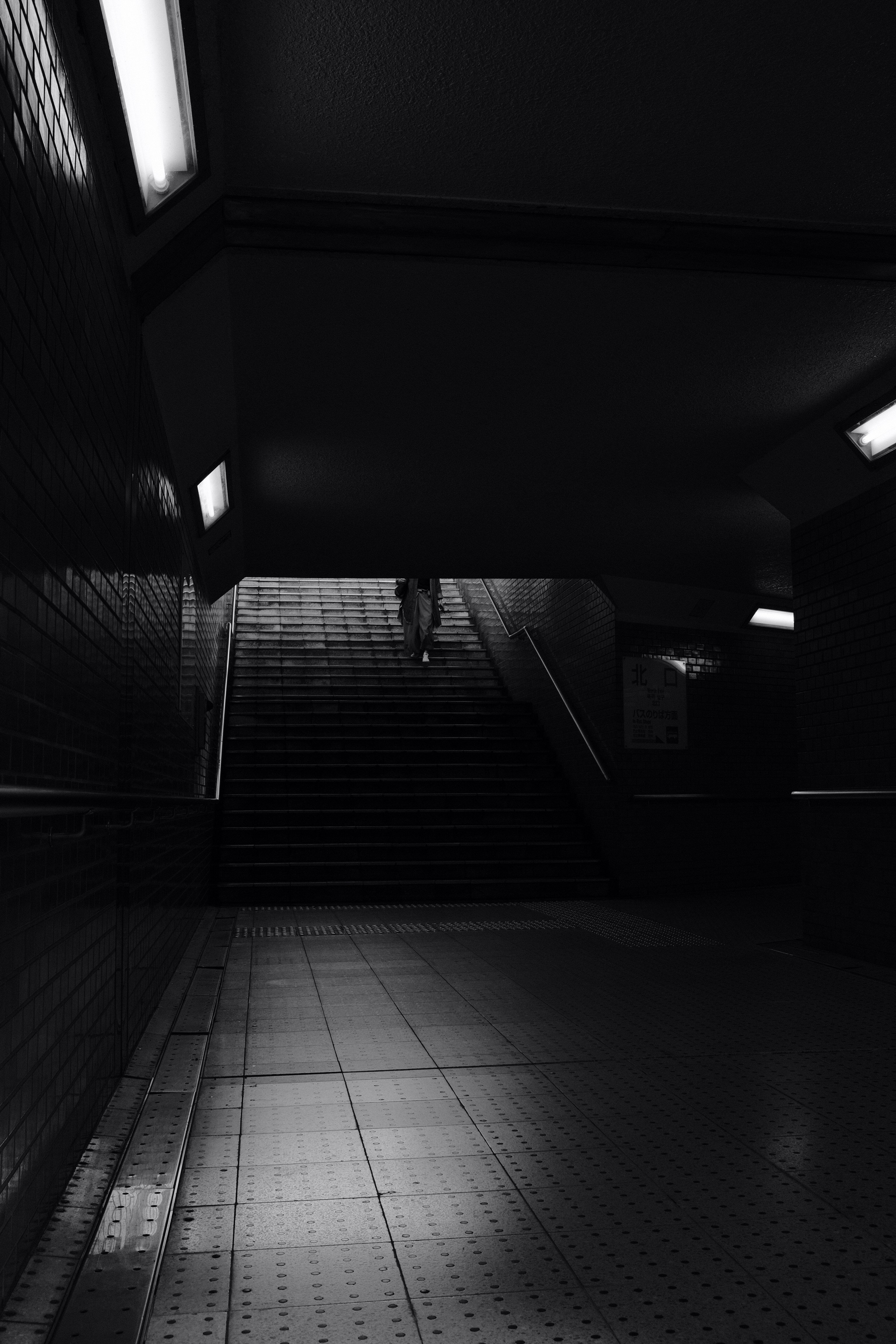 grayscale photo of man walking on hallway