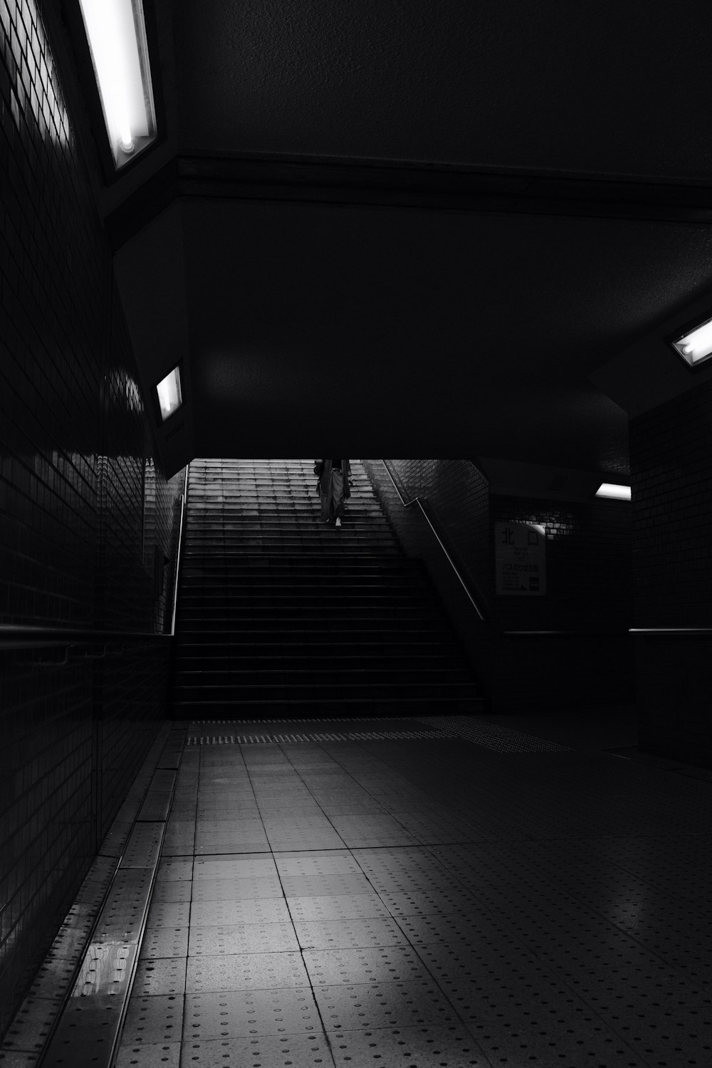 grayscale photo of man walking on hallway