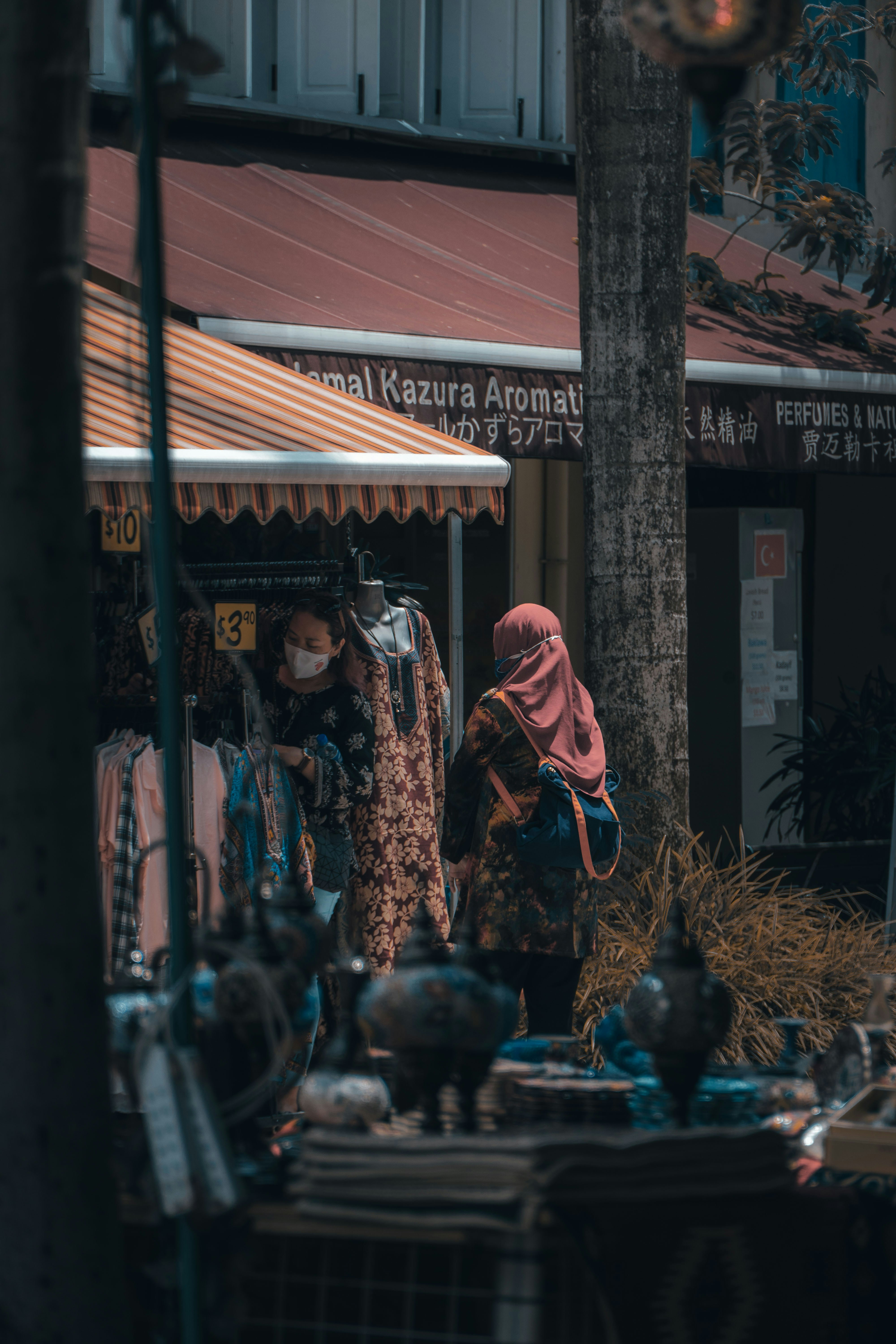 woman in red hijab standing near brown wooden post during daytime