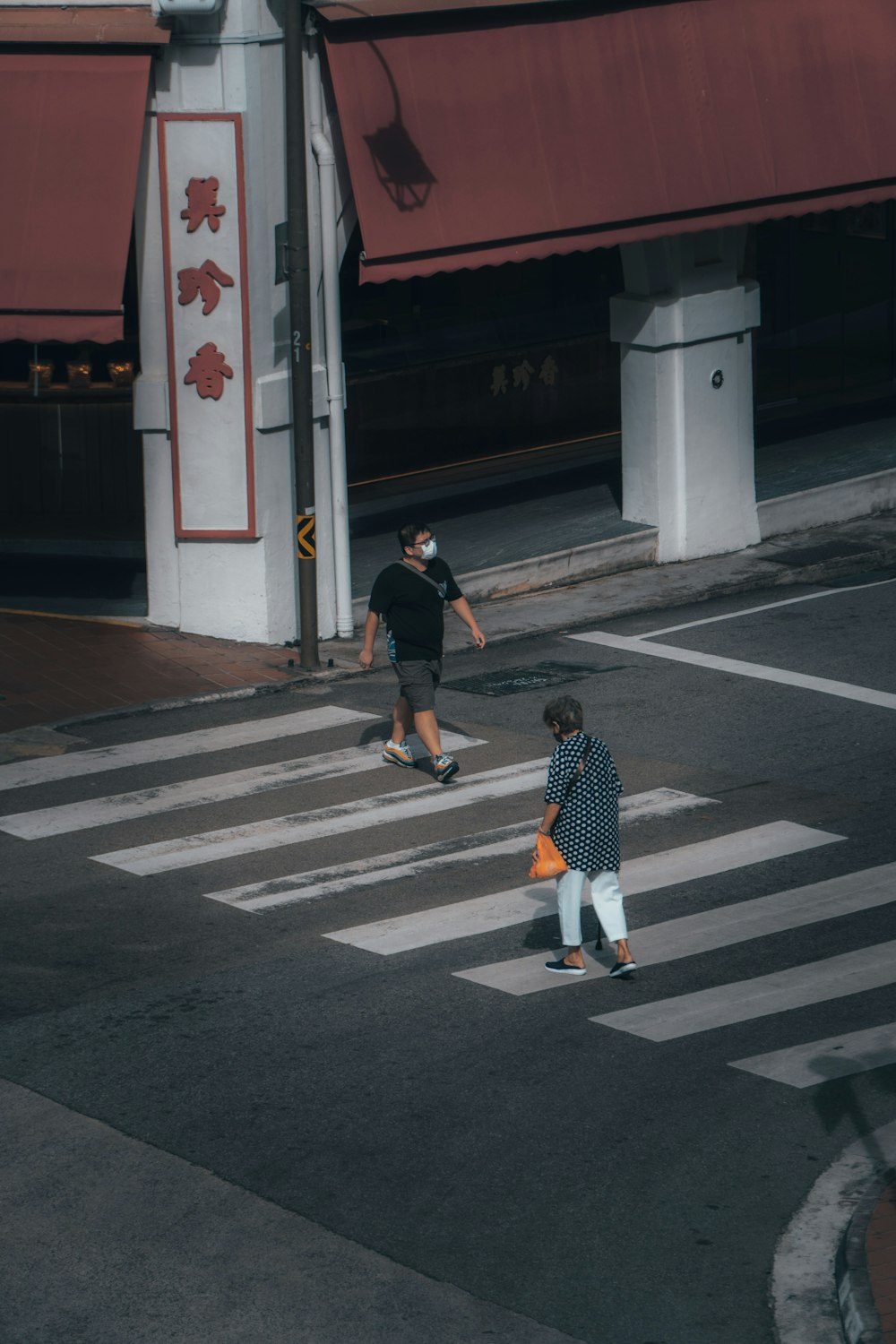 man in black shirt and white shorts walking on pedestrian lane during daytime