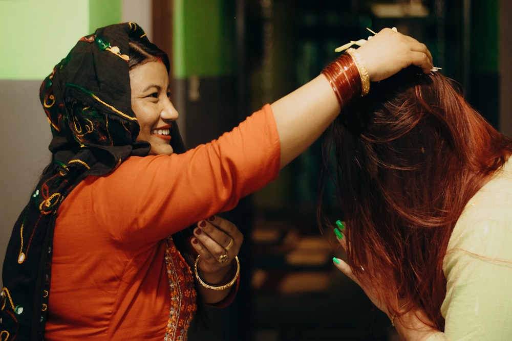 woman in orange long sleeve shirt holding her hair