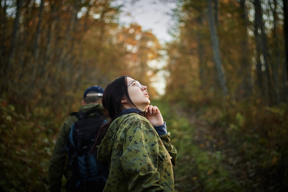 woman in green and black camouflage jacket standing in forest during daytime