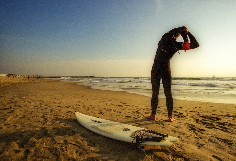 person in black wet suit holding white surfboard on beach during daytime