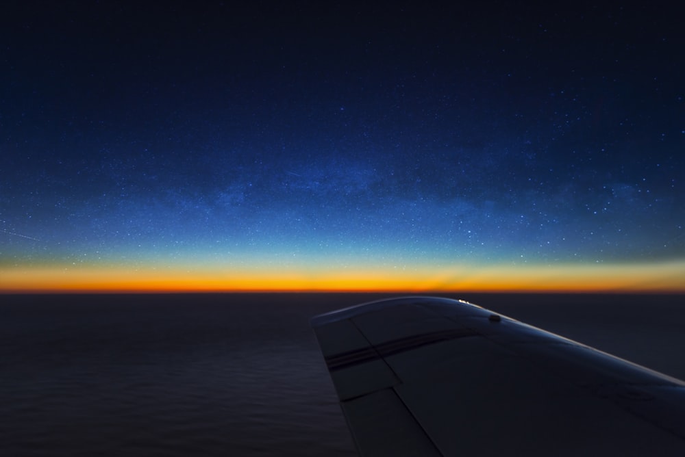 airplane wing over the blue sky during sunset