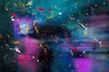 An abstract composition featuring a blend of colors and textures with splashes of vivid red, yellow, white, and orange paint scattered across a vibrant background of blue, teal, and purple tones. The image possesses a dynamic and chaotic aesthetic, resembling paint splatters or cosmic imagery.