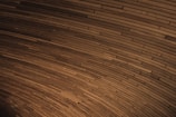 A curved pattern of wooden planks tightly arranged to create a visually engaging texture. The planks vary slightly in shade, contributing to a dynamic yet harmonious visual effect.