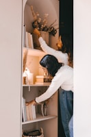 woman in white long sleeve shirt and blue denim jeans standing in front of mirror