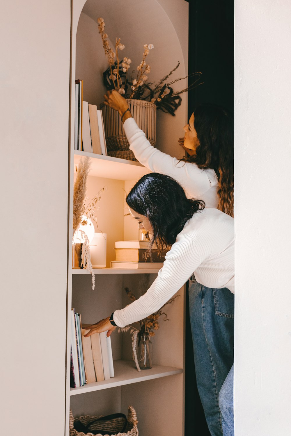 woman in white long sleeve shirt and blue denim jeans standing in front of mirror