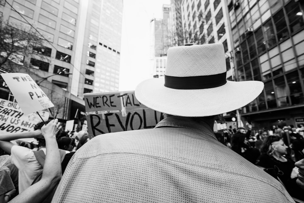 Photo en niveaux de gris d’un homme portant un chapeau et un manteau