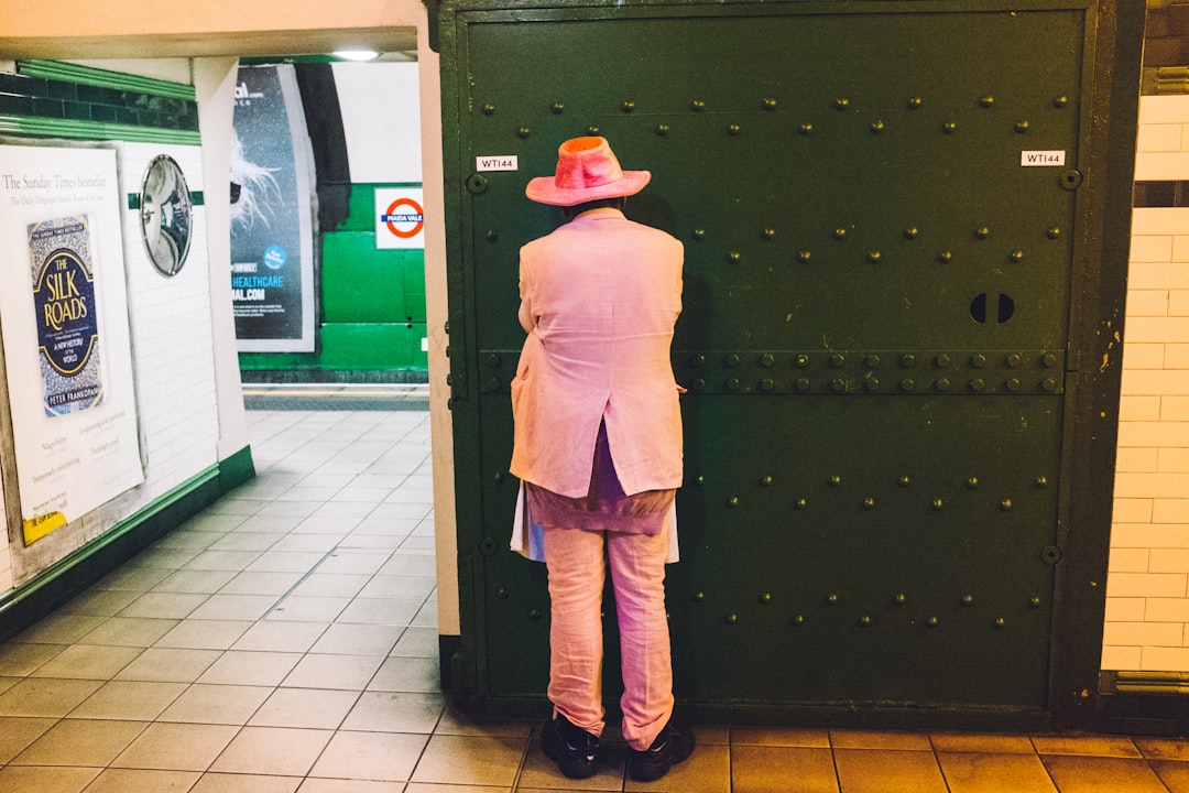 person in pink robe and brown pants standing near black wooden door