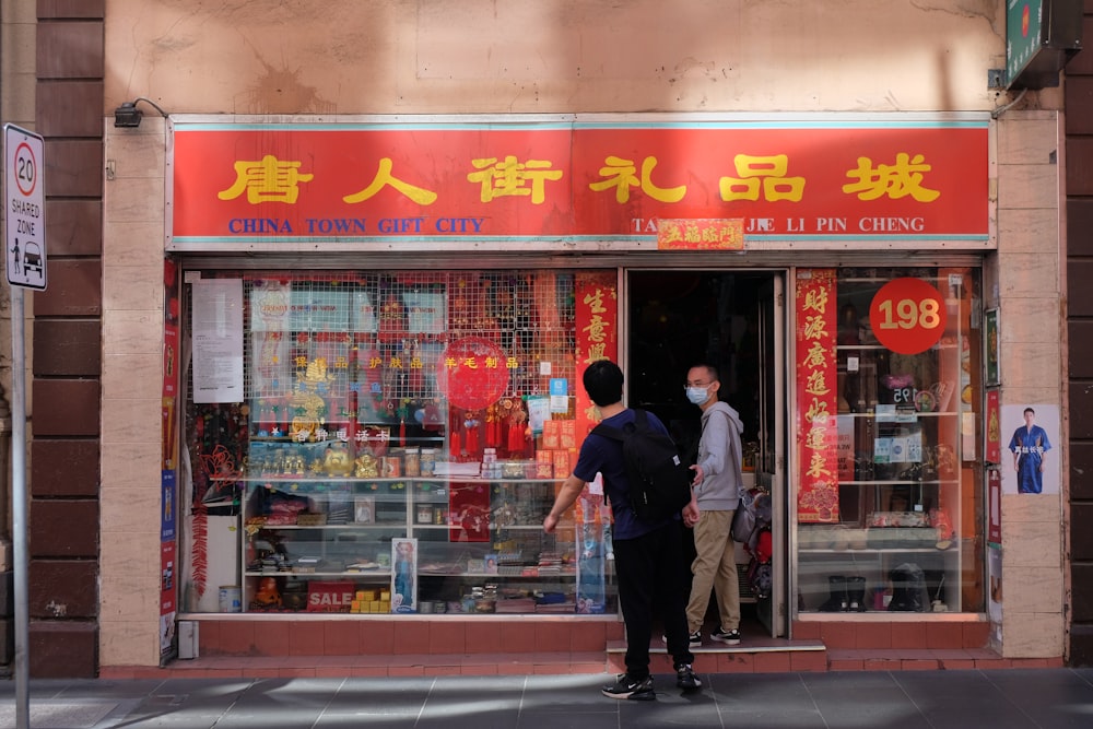 man in black jacket and blue denim jeans standing in front of store