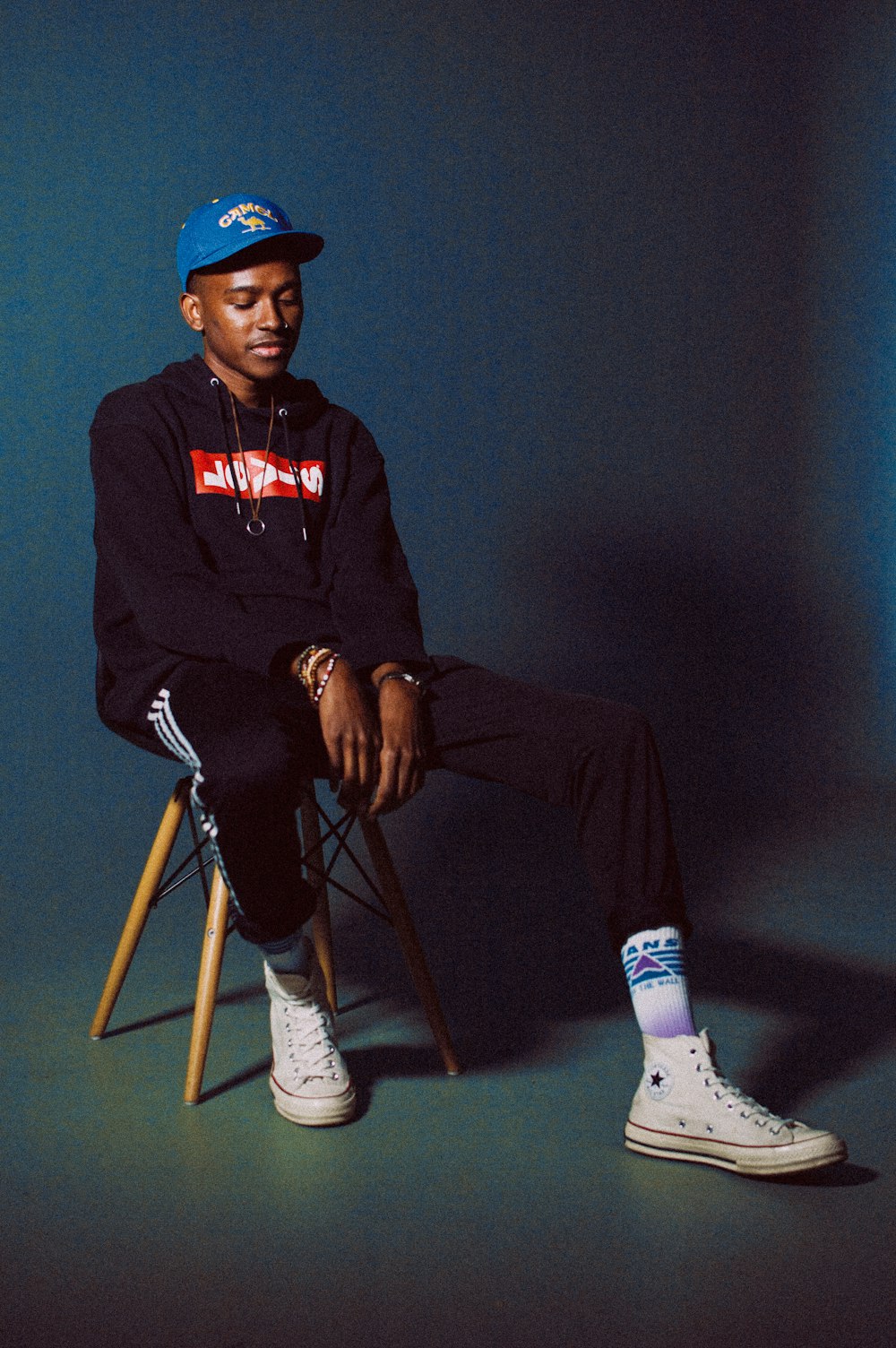 man in black and white new york yankees hoodie and black fitted cap sitting on chair