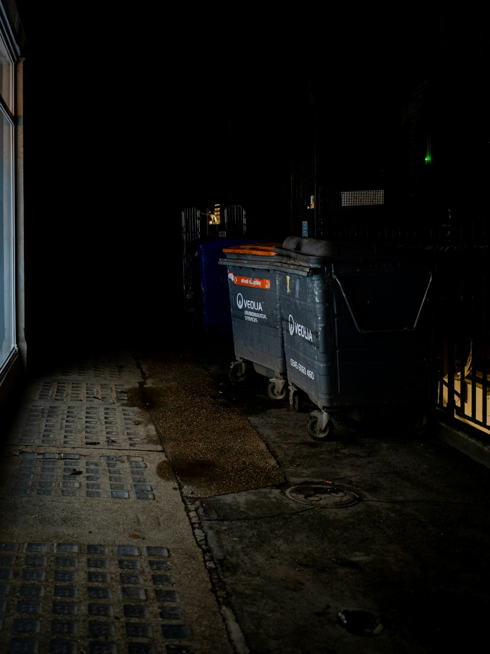 blue plastic trash bin beside white wall