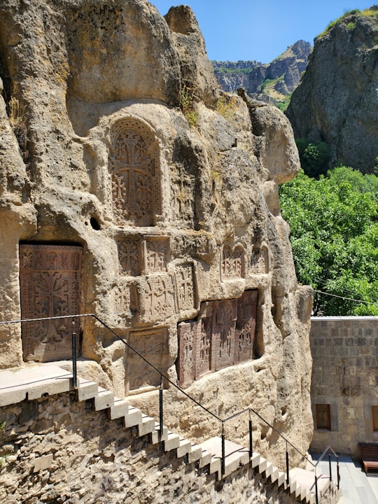 brown concrete building near green trees during daytime in Geghard Armenia