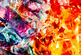 An abstract composition featuring vibrant colors and intricate textures. The swirling patterns create a sense of movement with bold reds, oranges, and blues blending together, resembling a fiery explosion.