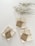 Three neatly folded stacks of beige cloth napkins tied with twine, each with a brown kraft tag labeled 'ernest & lulu.' Above them, delicate sprigs of dried flowers with small white blossoms lay against a neutral background.