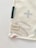 A corner of a fabric piece with an attached label displaying the text 'ernest & lulu' and a website URL. The fabric features printed abstract shapes in soft colors, bordered by stitching.