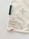 A corner of a fabric piece with an attached label displaying the text 'ernest & lulu' and a website URL. The fabric features printed abstract shapes in soft colors, bordered by stitching.