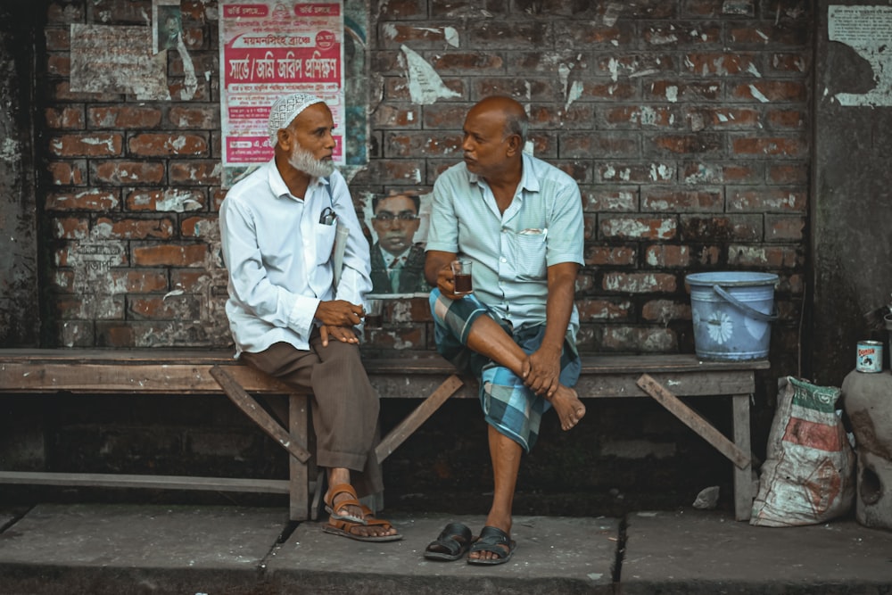 man in white button up shirt sitting on brown wooden bench