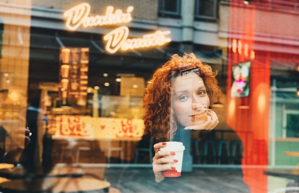 woman in brown knit cap holding white disposable cup