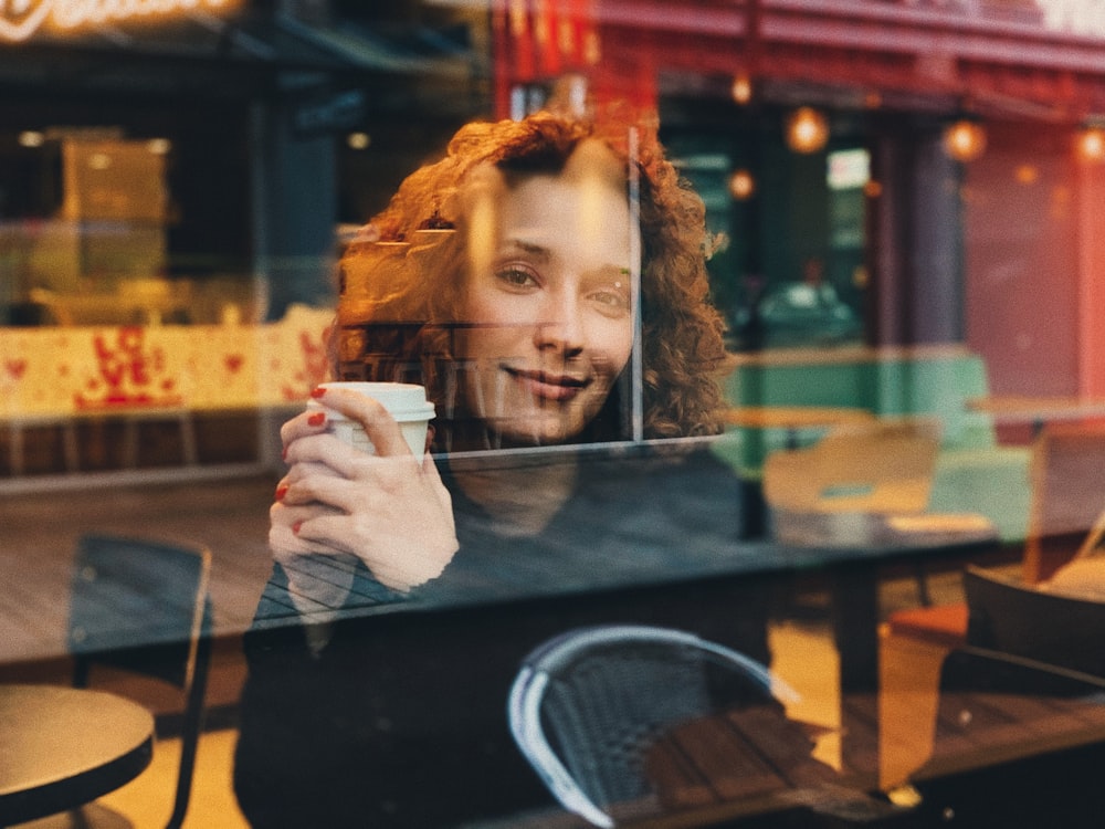 woman in black long sleeve shirt holding white disposable cup