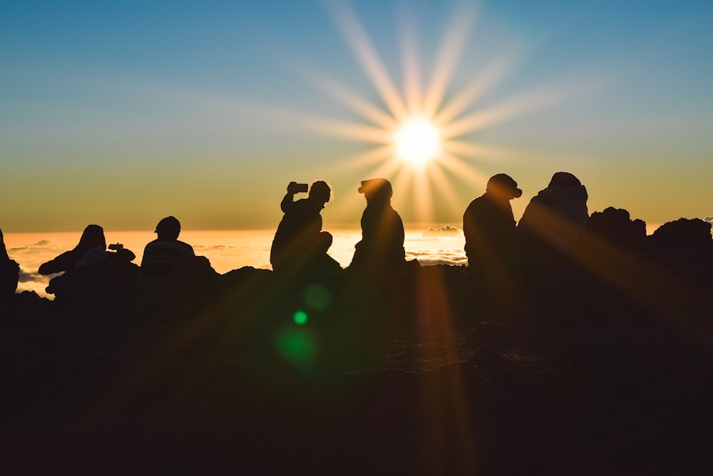 silhouette of people sitting on beach during sunset