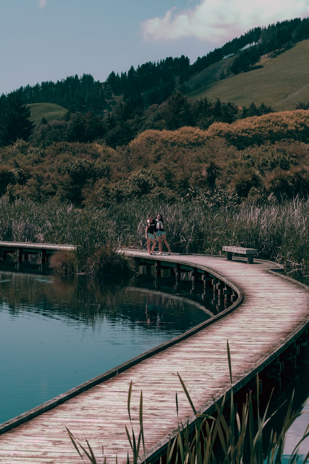 woman in black shirt and black pants sitting on brown wooden dock during daytime