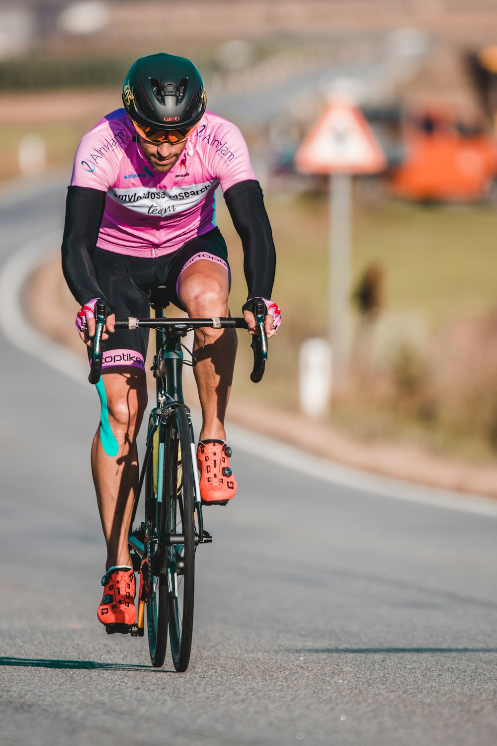 man in black and pink jacket riding on black bicycle during daytime