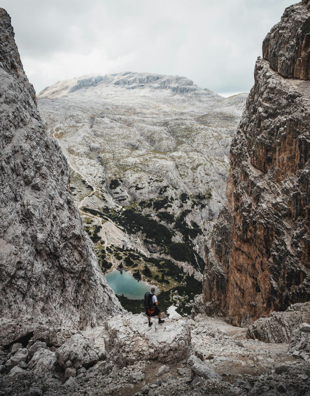 person in blue jacket and black pants standing on rocky mountain during daytime