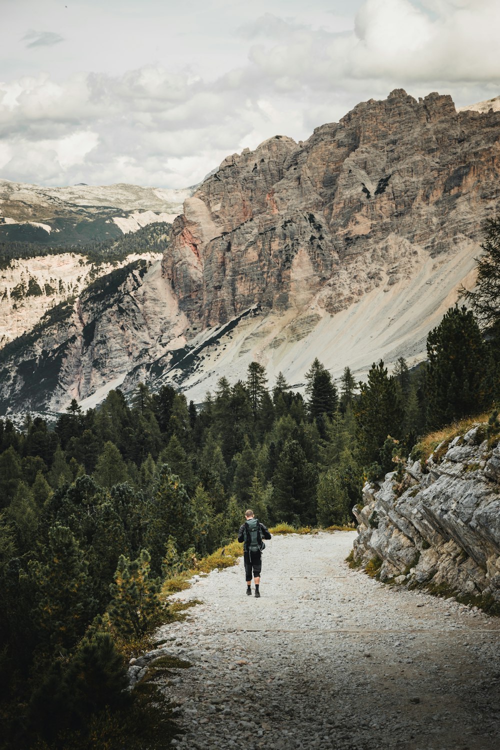 person in black jacket walking on brown dirt road during daytime