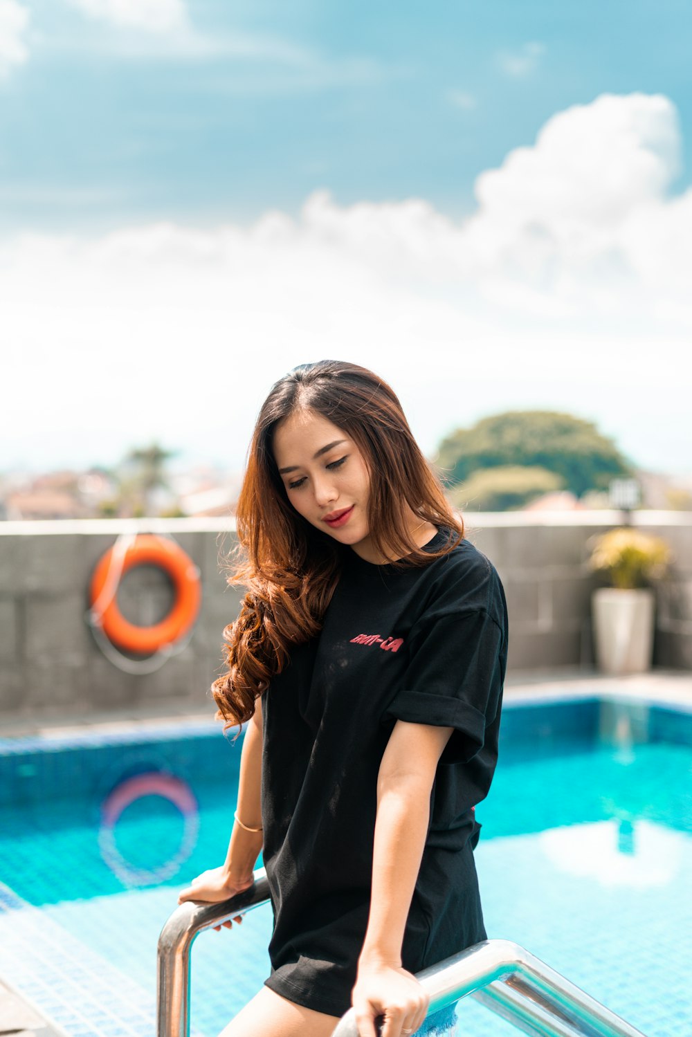 woman in black crew neck t-shirt standing near swimming pool during daytime