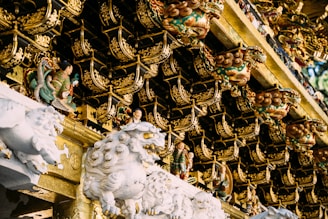 Intricately carved figures and ornate decorations adorn the roof of a traditional structure. The detailed craftsmanship features mythological creatures and small human figurines amidst elaborate golden patterns.