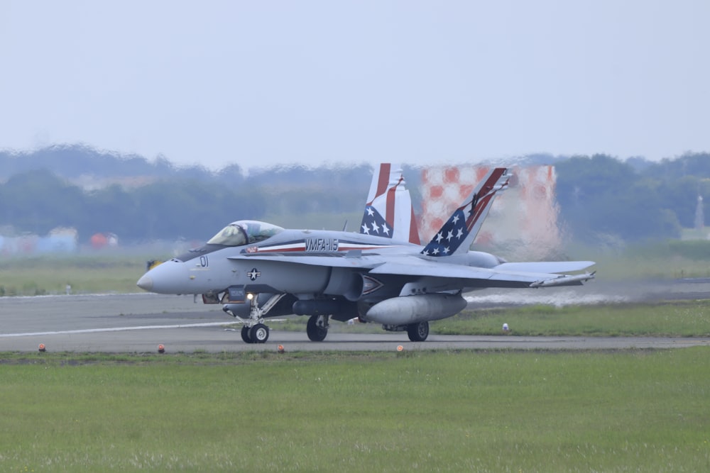 Grauer Kampfjet tagsüber auf grünem Rasen