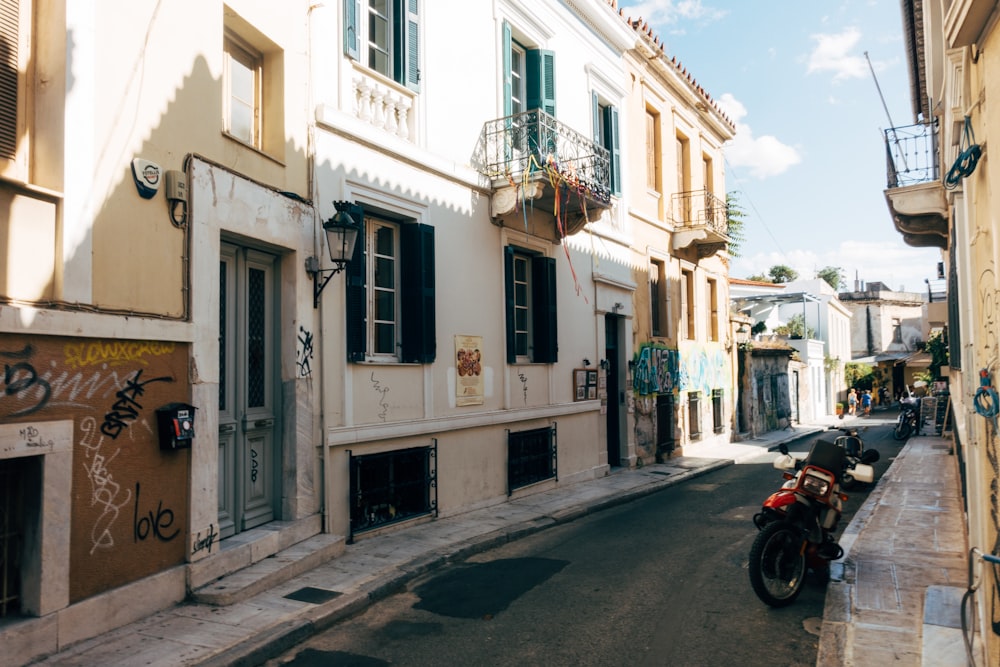 Motocicleta roja estacionada frente a un edificio de concreto blanco durante el día