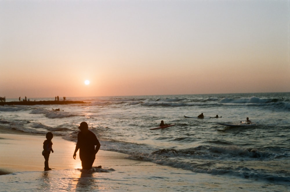 man and woman walking on beach during sunset