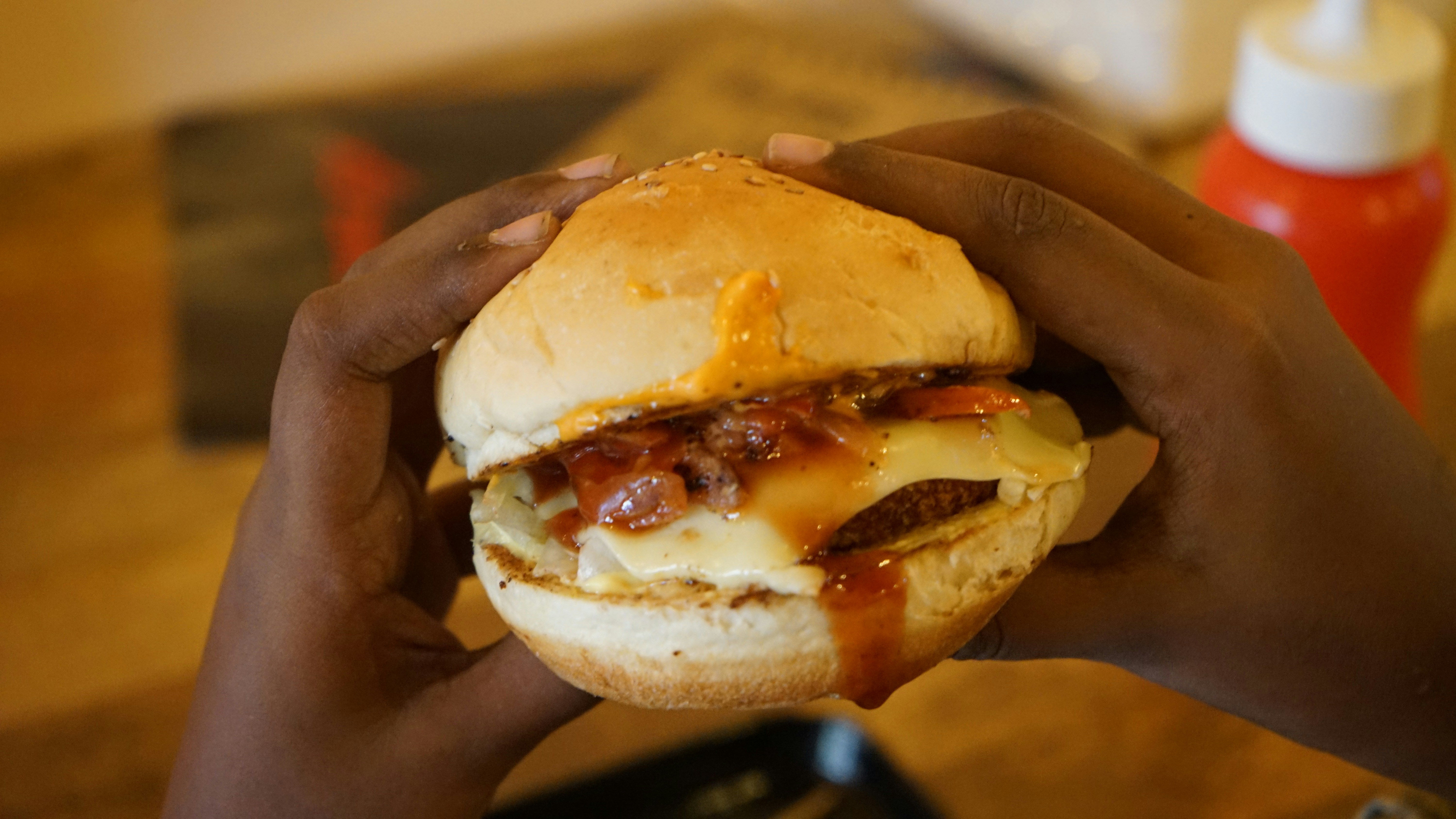person holding burger with cheese