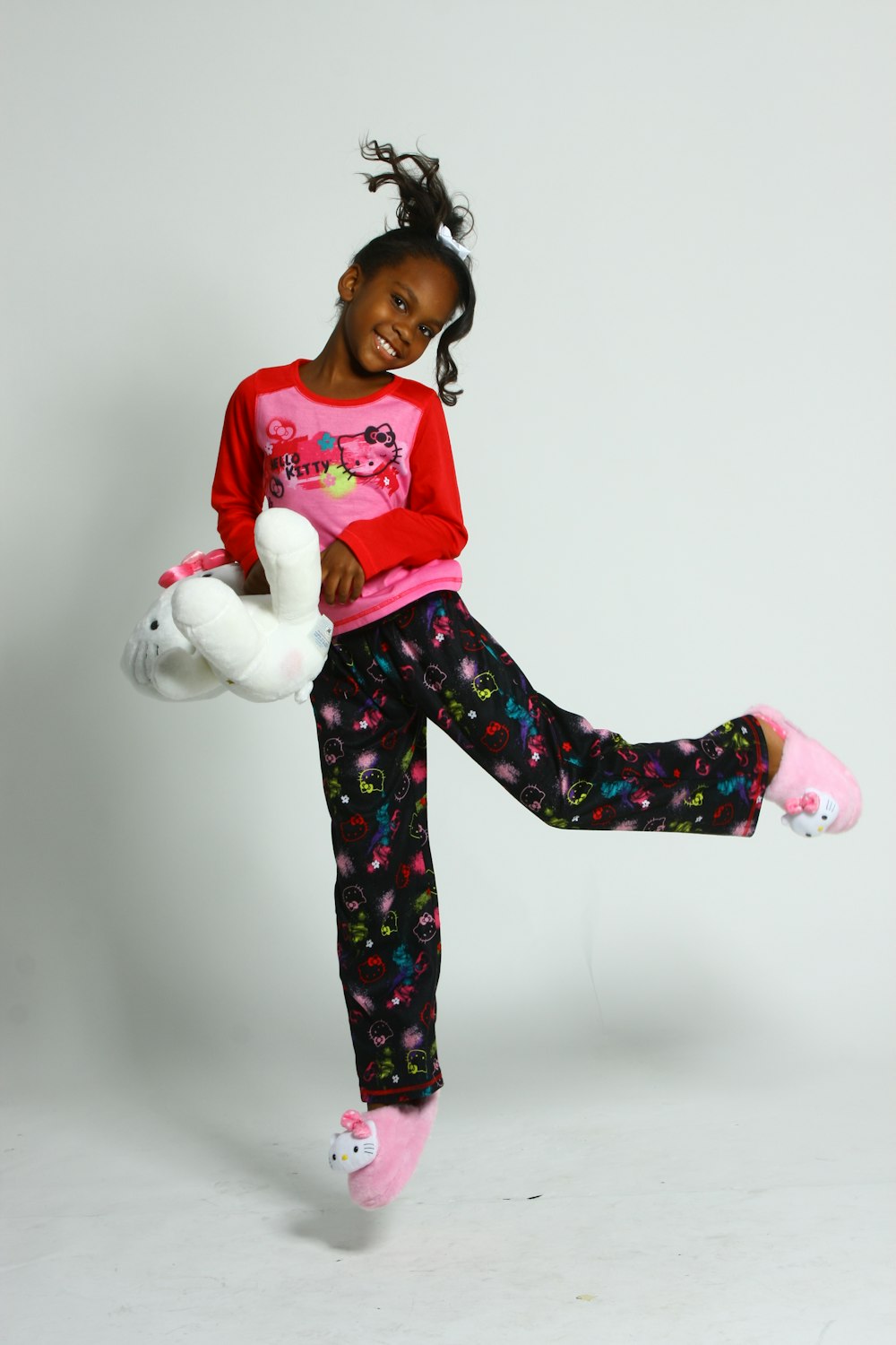 girl in pink and white long sleeve shirt and blue pants holding white plush toy
