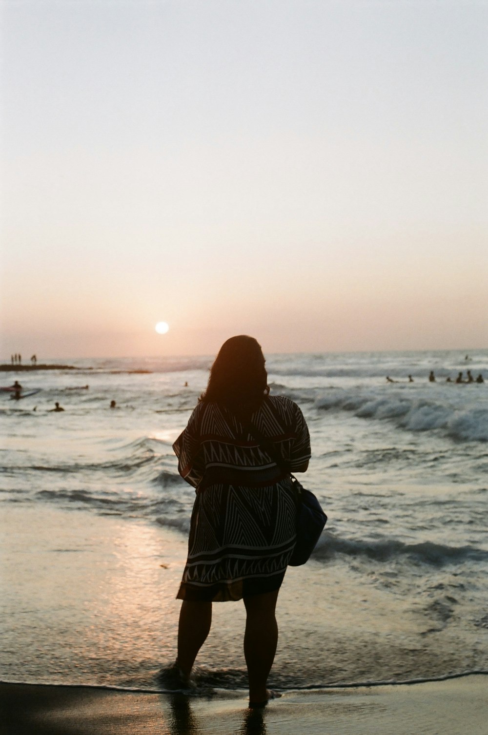 woman in black and white stripe dress standing on seashore during daytime