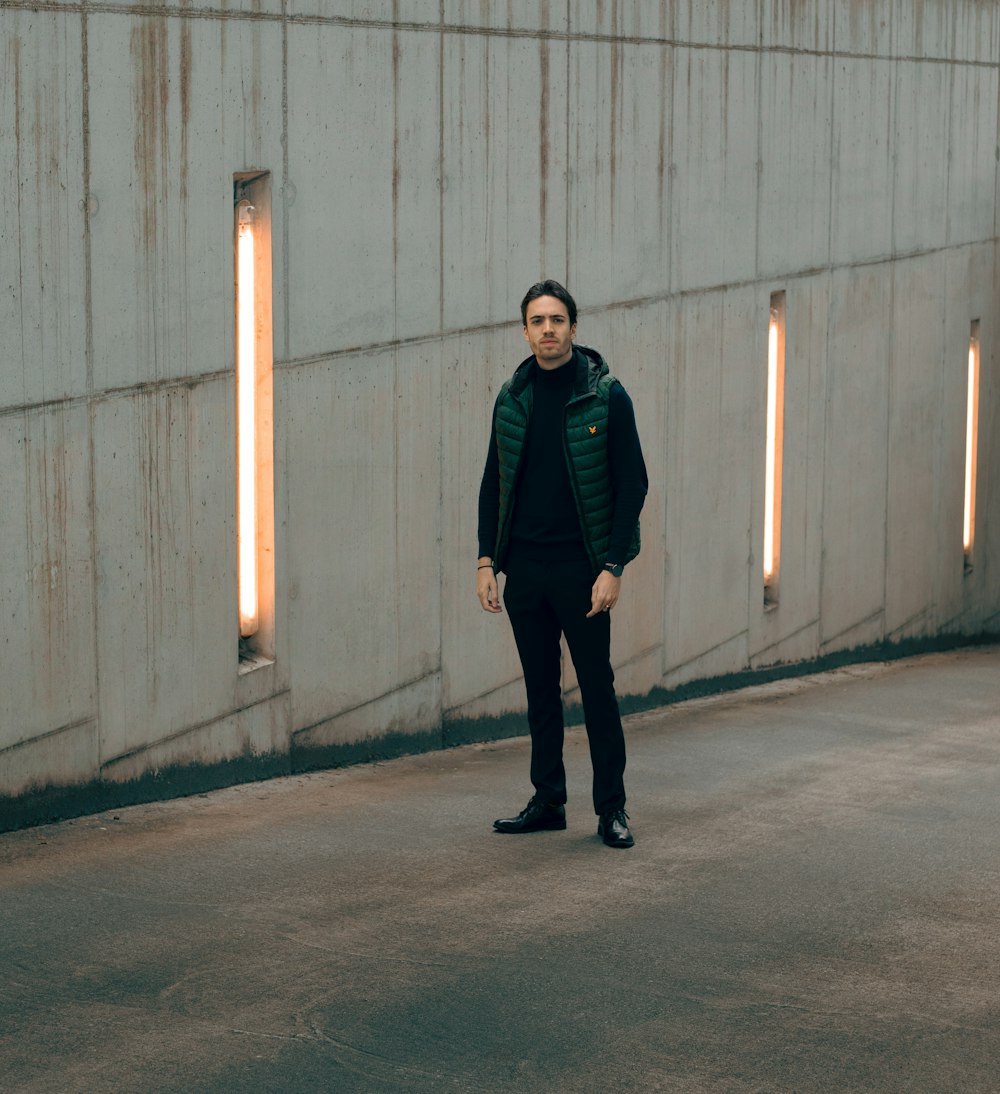 man in black jacket standing on gray concrete floor