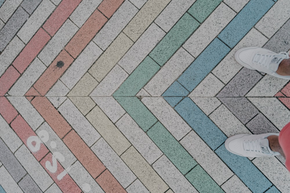 person in white sneakers standing on blue and white floor tiles