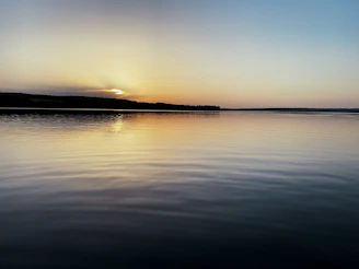 A peaceful sunset casting deep indigo hues over a calm lake horizon.