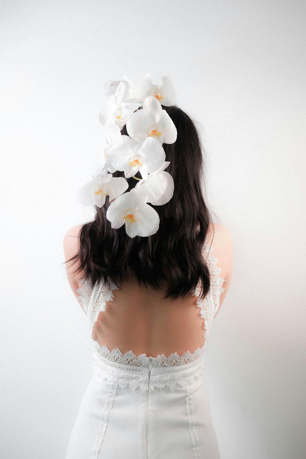 Frau in weißem Spitzentop mit weißer Blume auf dem Kopf