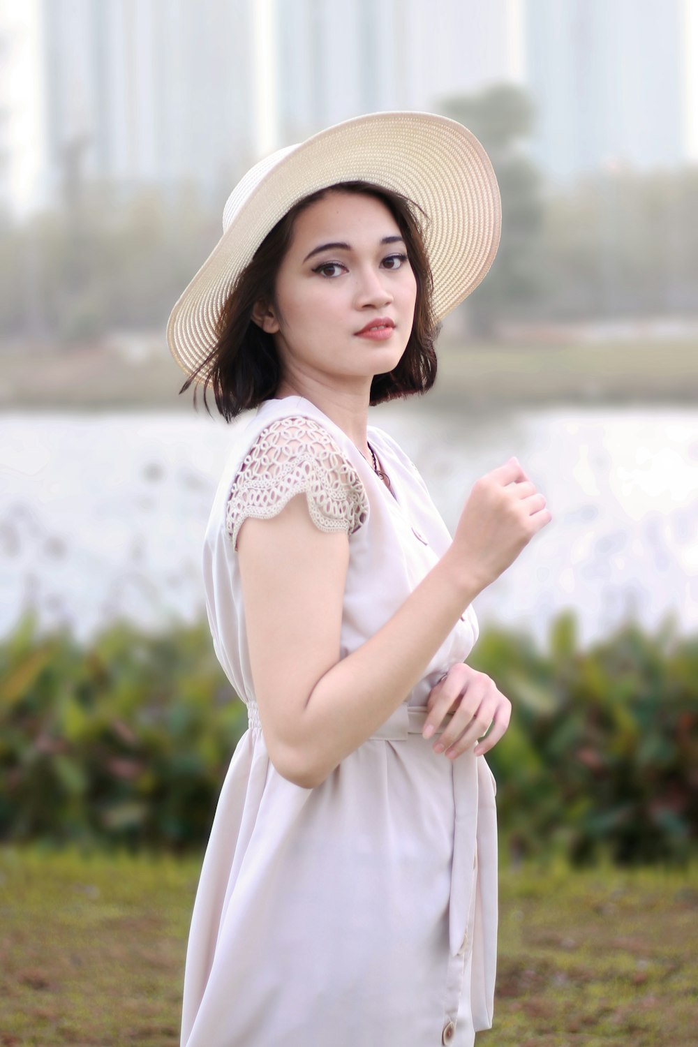 woman in white sleeveless dress wearing brown sun hat