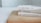 Three books are stacked on a wooden surface, with their spines partially visible. The names on the spines suggest they are foreign language books. Light colors dominate the scene, giving it a clean and minimalistic look.