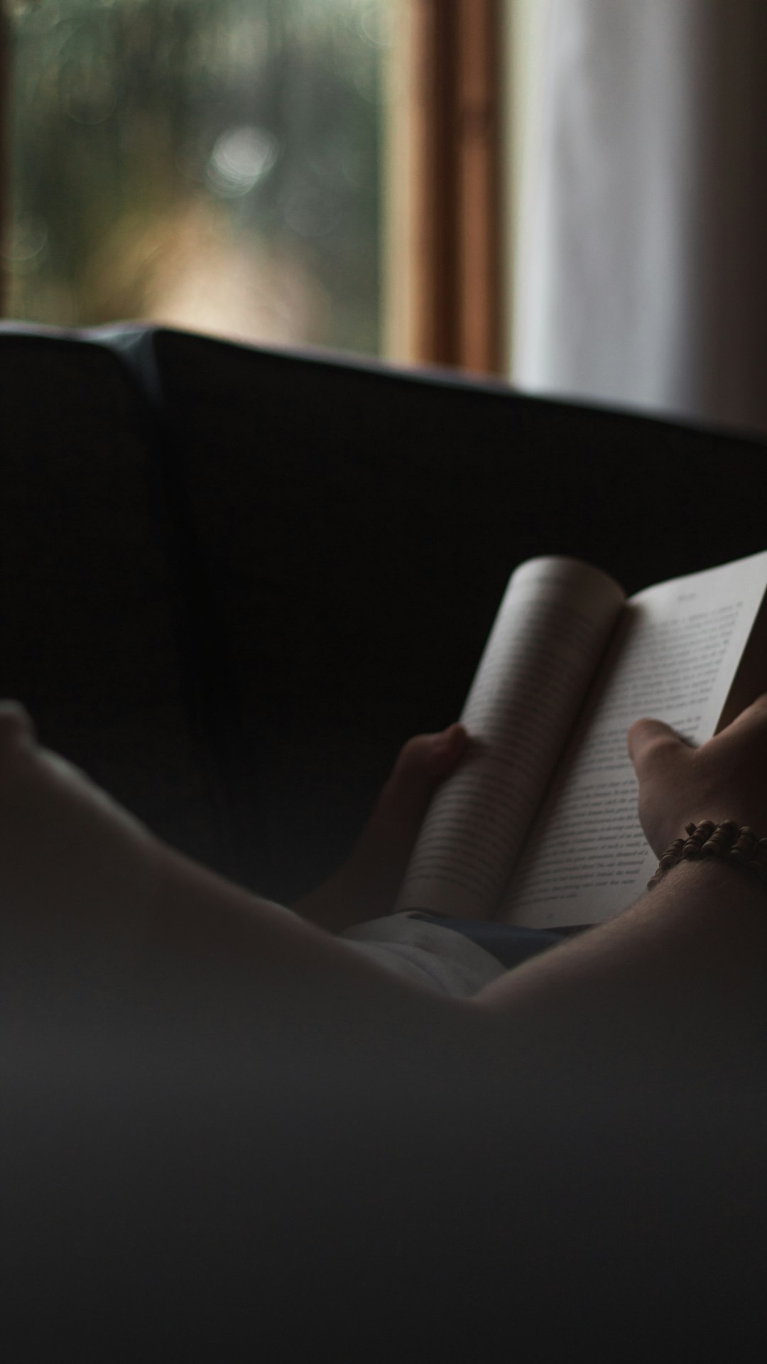 person reading book on black sofa